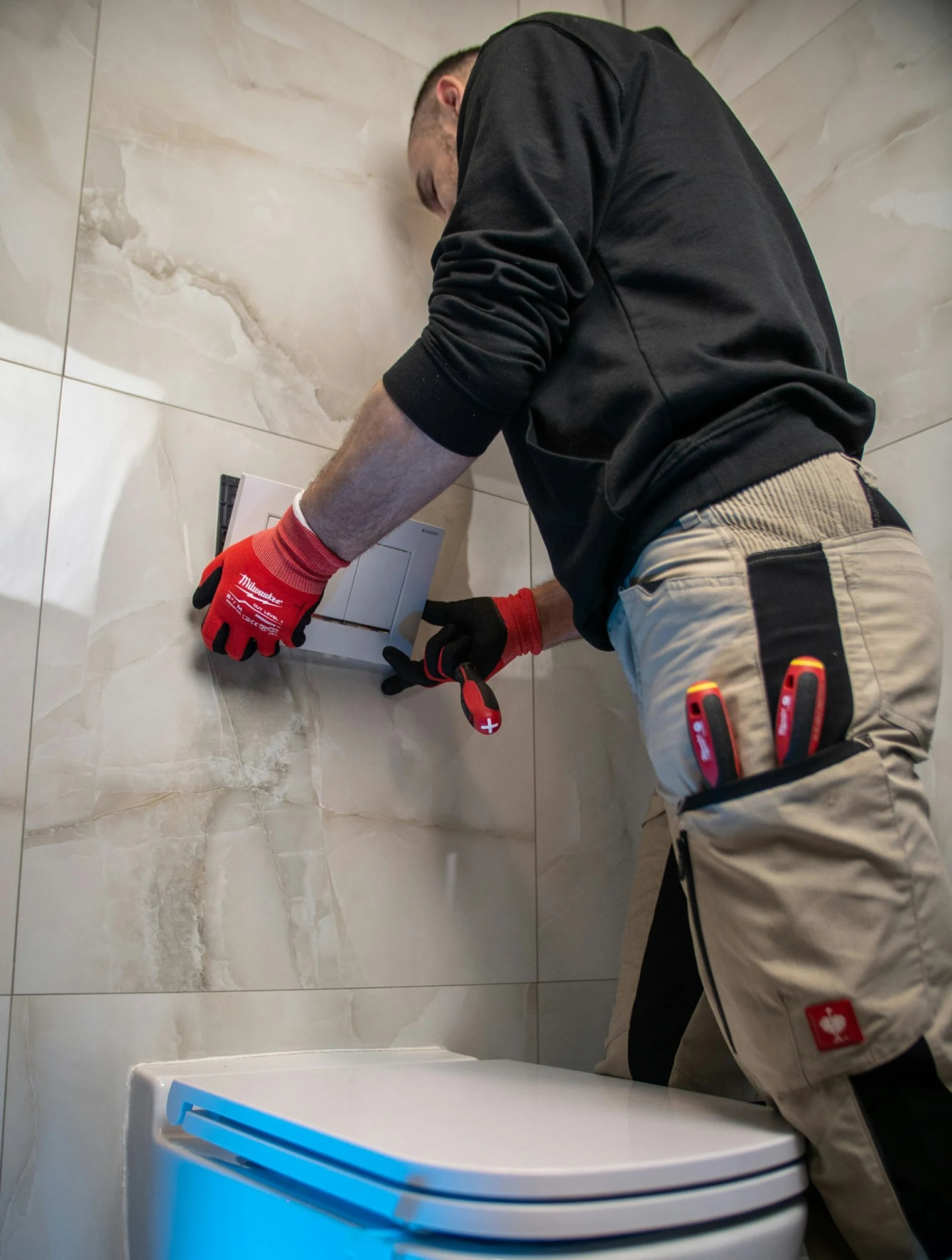 Installateur mit roten Arbeitshandschuhen bei der Montage